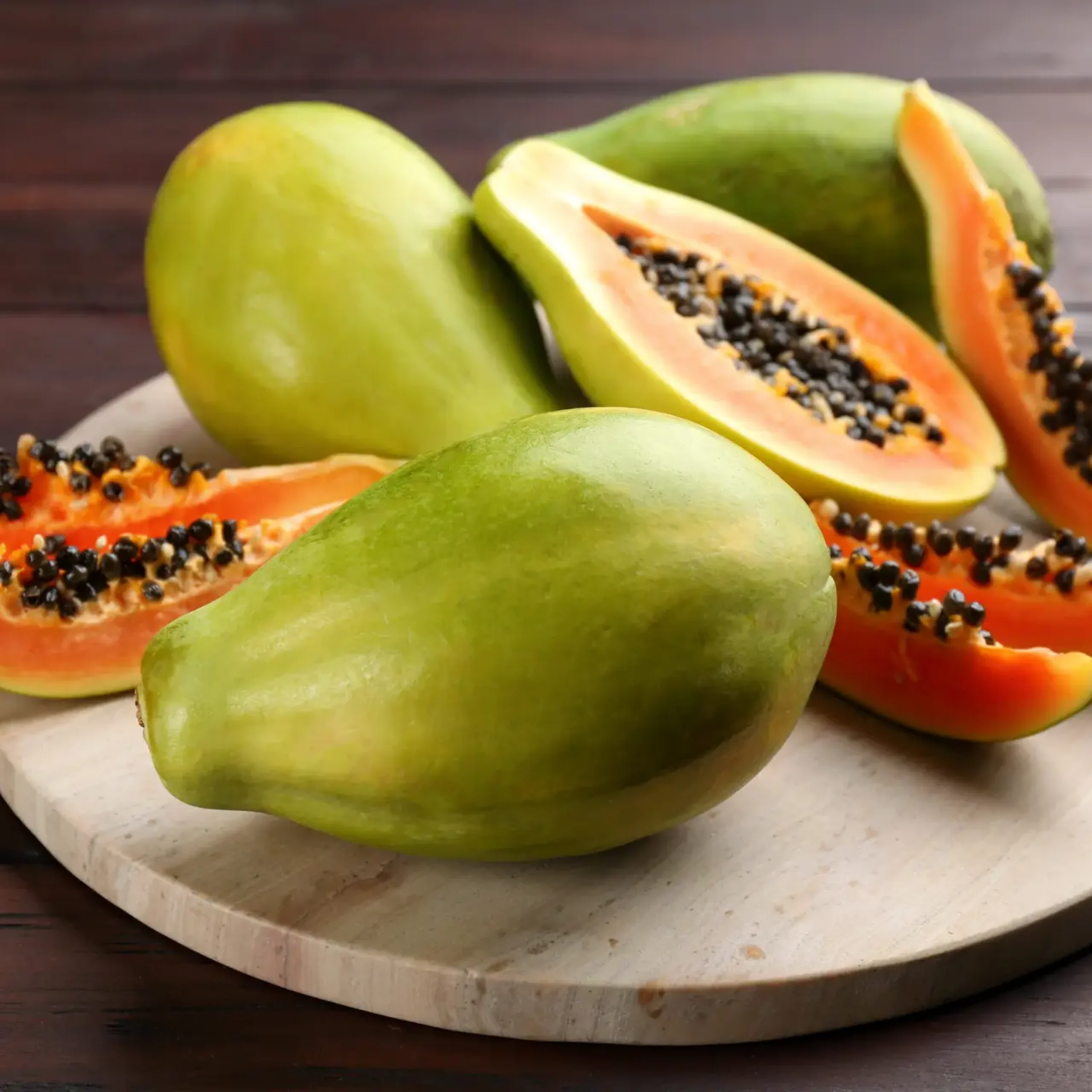 Cut and whole fresh ripe papaya fruits on wooden table